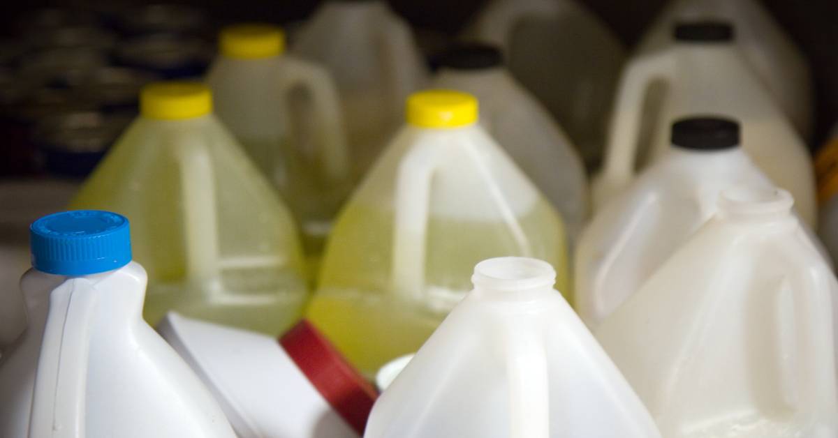 Various bottles of floor cleaning chemicals. The bottles have yellow, black, blue, or red caps. One bottle is open.