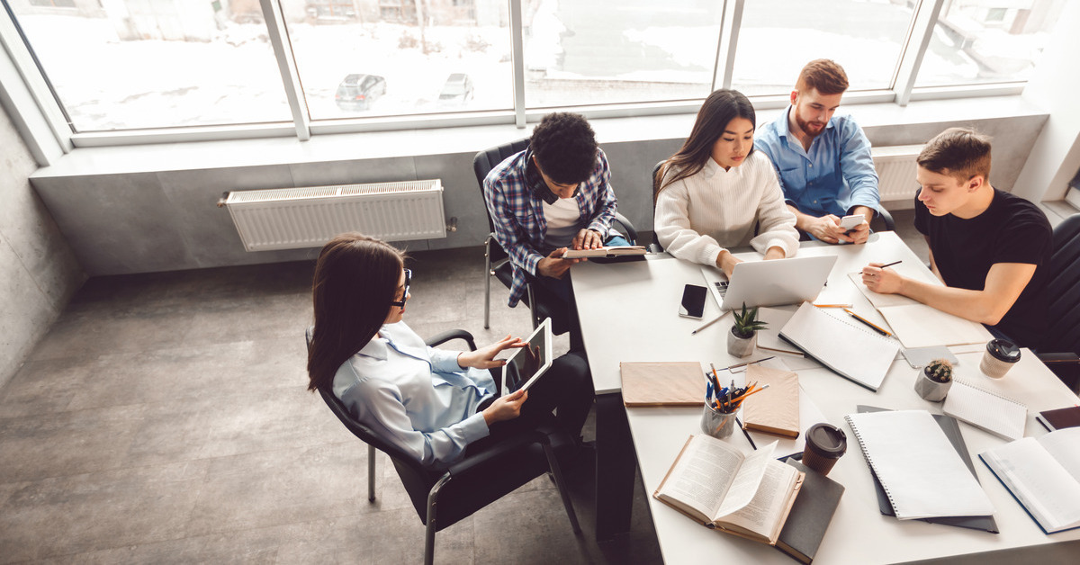 Employees in a clean office room are collaborating on a work task. The floor is clean, and the space is well-kept.